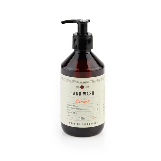 A pump bottle of hand wash with a label that reads 'HAND WASH Amber'. The bottle is made of dark amber glass with a black pump, and the label has white text and decorative elements.
