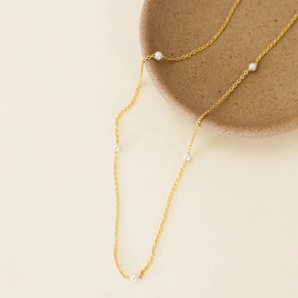 Gold necklace with pearls on a beige background