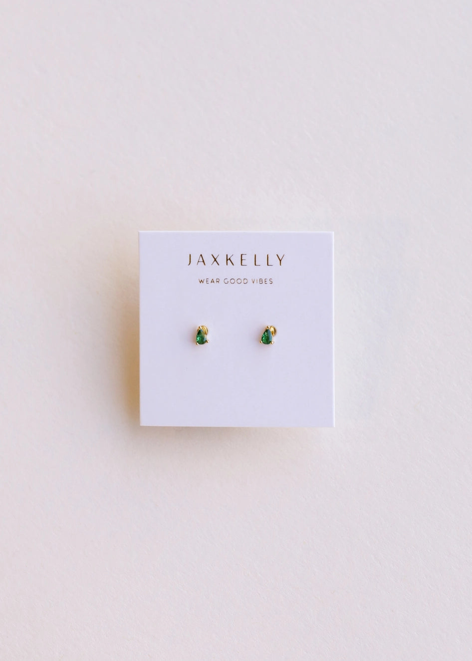 image of a pair of emerald teardrop stud earrings on plain background