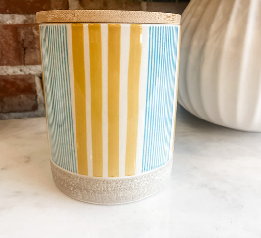 Striped storage tin with yellow, white, and blue vertical bands and speckled bottom