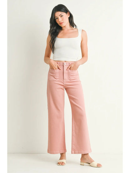 A pair of dusty coral wide leg pants with a high waist and button fly closure, displayed on a model without showing the upper part of the body.