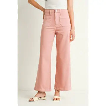 A pair of dusty coral wide leg pants with a high waist and button fly closure, displayed on a model without showing the upper part of the body.