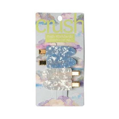 A set of four hair clips in two colors with a marbled design and metallic gold clasps on packaging 