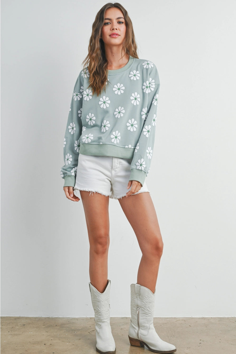 mint sweatshirt with daisies shown on model with boots and white shorts for fall outfit inspiration