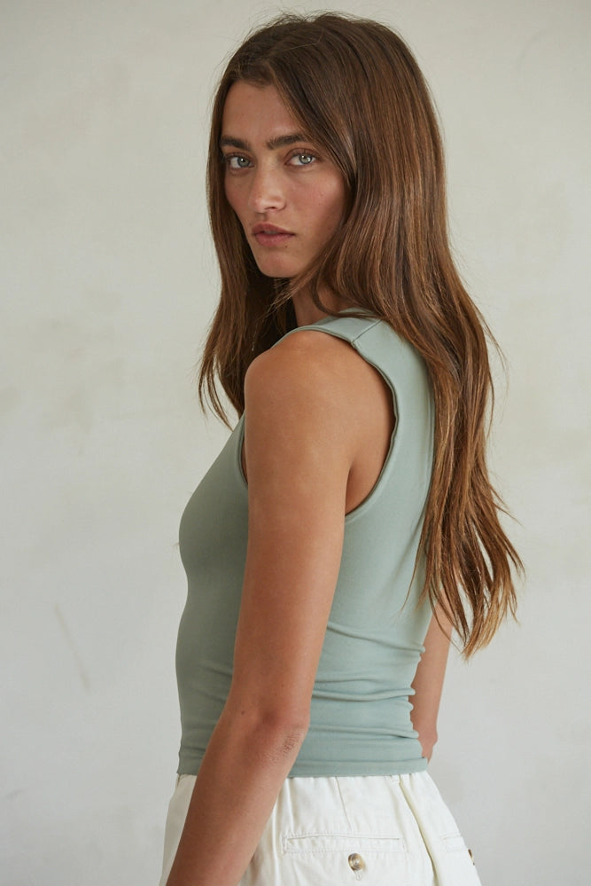 Woman wearing a light green tank top against a plain background