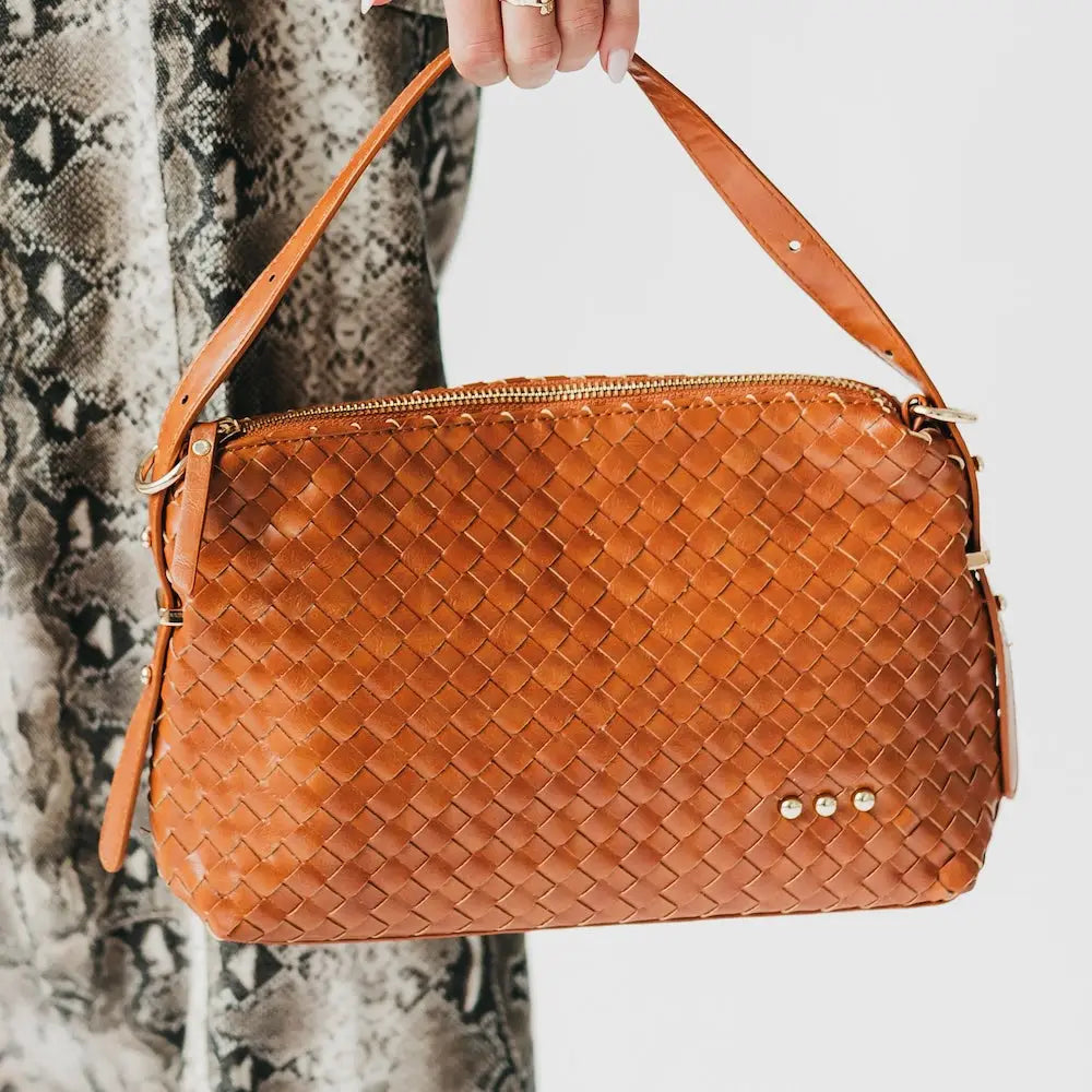 Woven orange shoulder bag with braided texture, zip top, and front stud detail