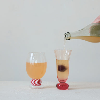 Pink drinking glass on ball stem, clear cup with pink drink