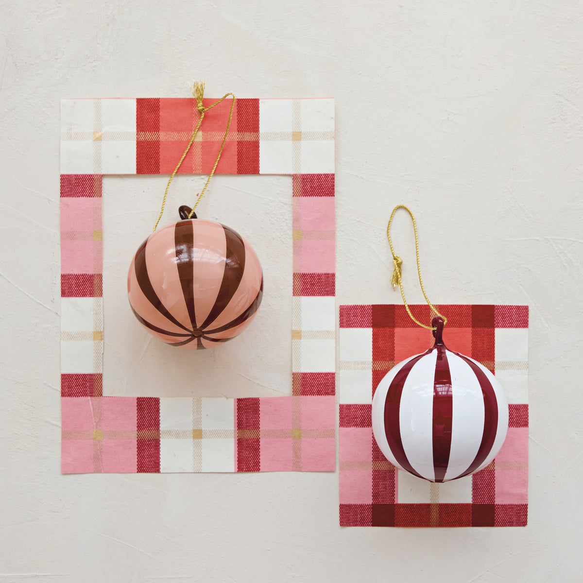 Striped glass ball ornaments in red/white and peach/red, each hanging from a gold hook.