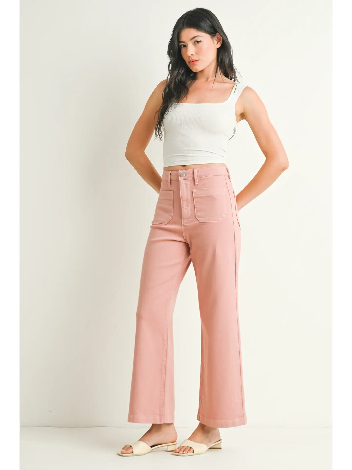 A pair of dusty coral wide leg pants with a high waist and button fly closure, displayed on a model without showing the upper part of the body.