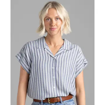 A woman wearing a blue and white striped button-down blouse with rolled up sleeves, paired with jeans.